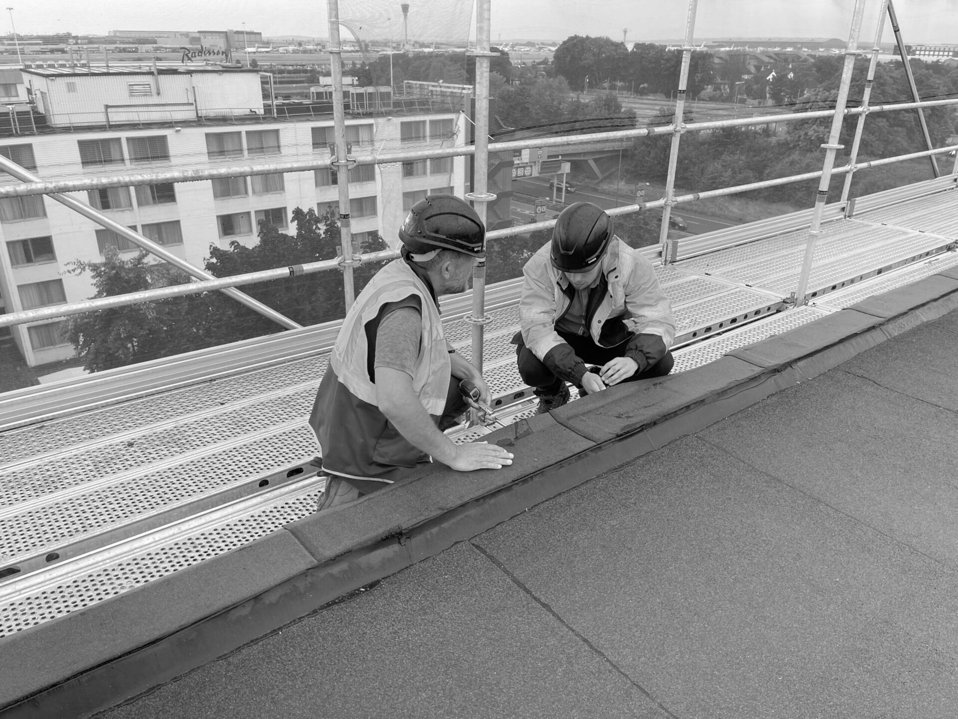 A photo of 2 construction workers working on a roof.