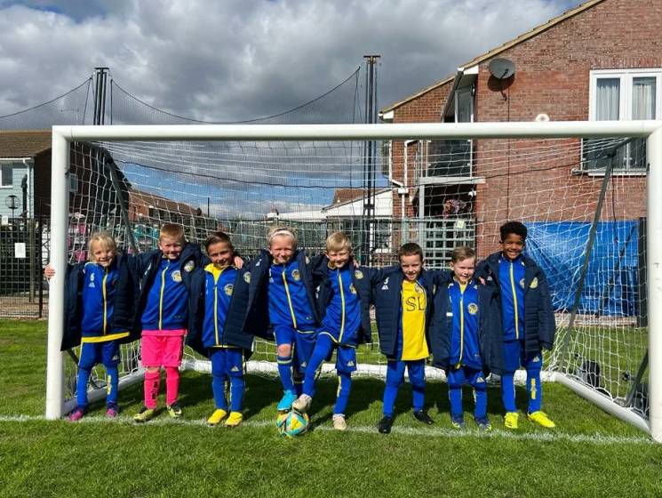Photo of a kids football team stood in a goal.